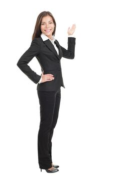 Businesswoman showing / pointing at copy space in full length. Confident mixed race chinese / caucasian woman isolated on white background. 