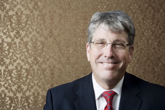 Corporate executive smiling broadly in front of a gold background