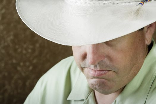 Man beneath a white cowboy hat in front of a gold background
