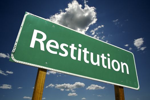 Restitution Road Sign with dramatic clouds and sky.
