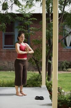 Pretty Young Woman doing Yoga on a Porch Looking Towards the Camera