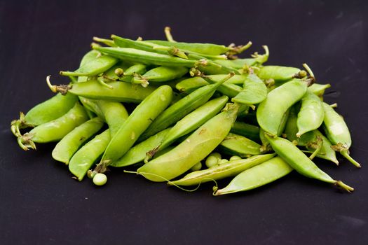 Green peas pods on a black background