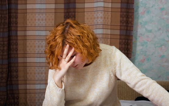 Young depressed woman sitting on the bed