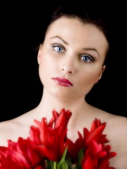 Portrait of young beautiful woman with red tulips on black background