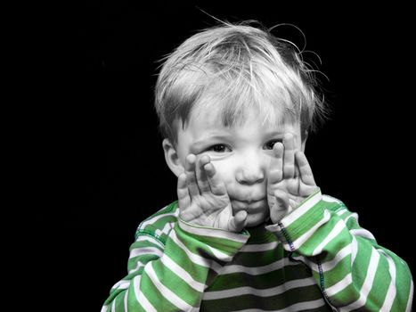 Litlle boy showing hands on black background, monochrome picture with only color green