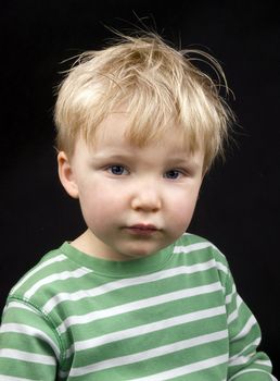 Portrait of little boy on black background. Boy have blond hair and blue eyes
