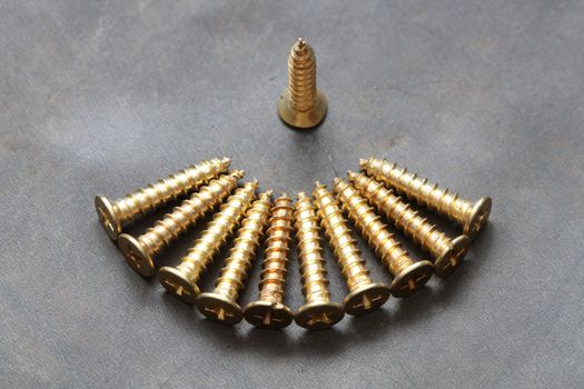 Closeup of few brass screws on dark metal background
