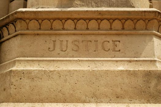 Word justice carving on a brown stone element