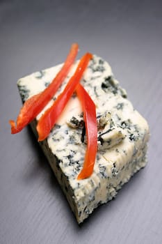 Blue cheese and red peper on a black background