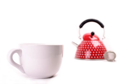 Cup in the foregrund and red teapot in the background