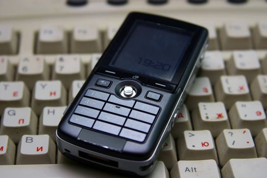 Black mobile phone on a dirty keyboard.