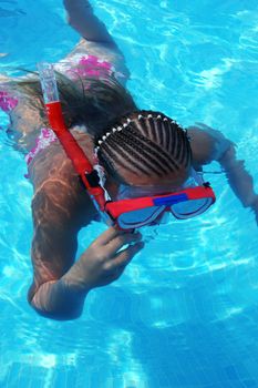 Young girl swimming underwater with snorkel and googles