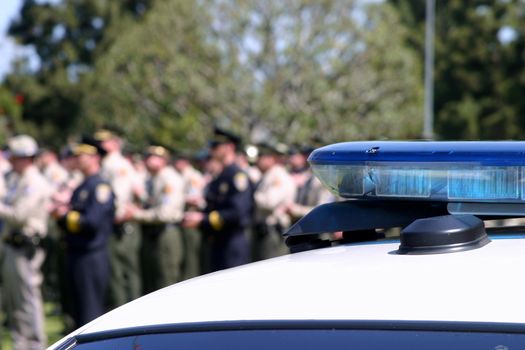 Top of a police car with police officer in the background.