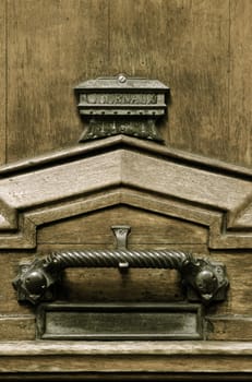 Close up macro shot of old wooden door and door furniture: ironmongery, letterbox, knocker with copy space
