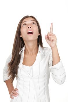 Woman pointing and looking up. Casual young businesswoman in white shirt looking and pointing surprised up at copy space. Attractive young mixed race chinese / caucasian woman isolated on seamless white background. 