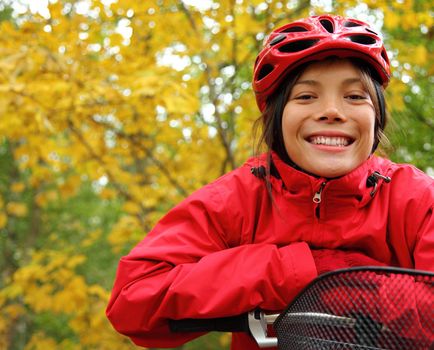 Biking. Woman in red on bike in autumn forest.