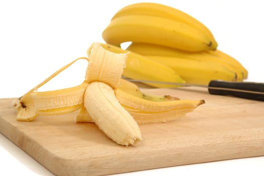 Bananas on a carving board on white bagground.