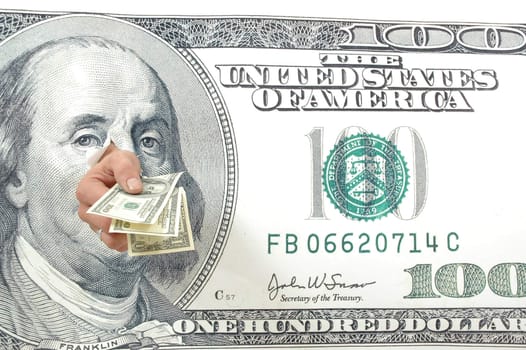 Hand holding hundred dollar bills through a large hundred dollar bill 
