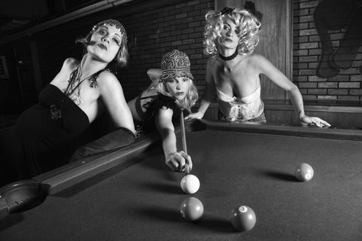 Three prime adult retro Caucasian females shooting pool.