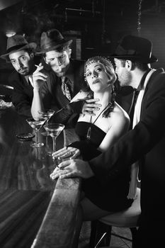 Caucasian prime adult retro female sitting at bar surrounded by suitors.