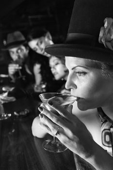 Caucasian prime adult retro female sitting at bar drinking martini.