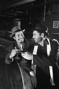 Caucasian prime adult retro males sitting at bar drinking.