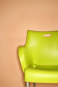 Green plastic chair against orange wall.