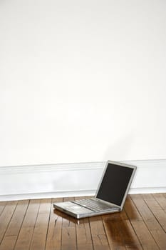 Still life of laptop on hardwood floor.