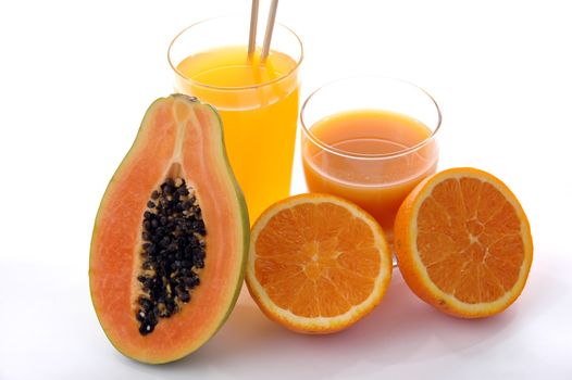 a glass of orange juice with cut oranges and papaya