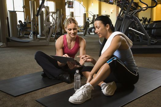 Prime adult Caucasian female with personal trainer at gym.