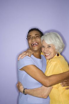 Caucasian and African American mature adult female embracing.