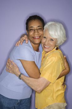 Caucasian and African American mature adult female embracing.