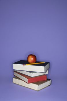 Stack of books with apple and pencil.