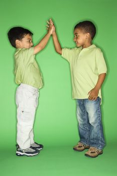 Hispanic and African American male child giving high five.