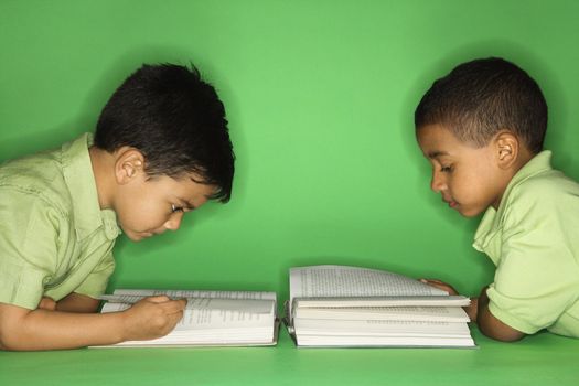 Hispanic and African American male child lying reading.