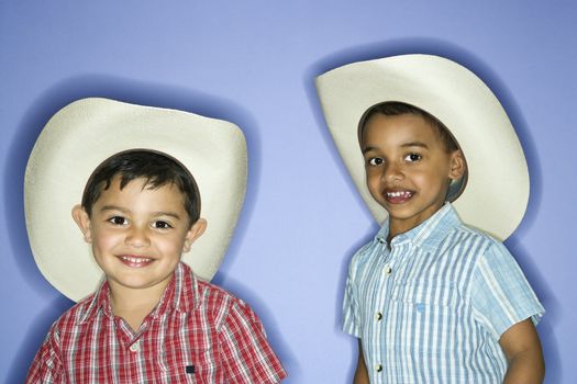 Hispanic and African American male child in cowboy hats.