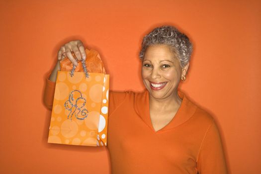 African American mature adult female holding gift bag.