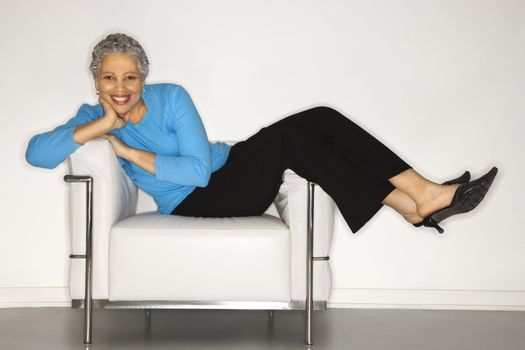 African American mature adult female lying back on chair.