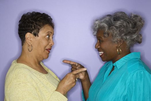 Mature adult African American females pointing at eachother.