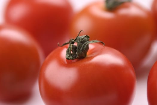 Closeup of red tomatoes, one in front and other ones blurred out in the background