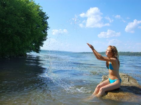 happy girl having fun in the lake wit water drops