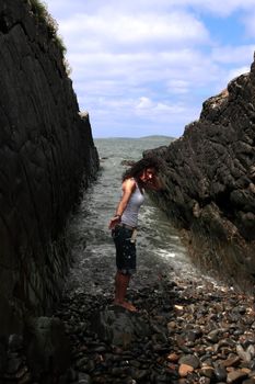 a beautiful woman practicing her yoga on the rocks in a ravine as the waves roll in