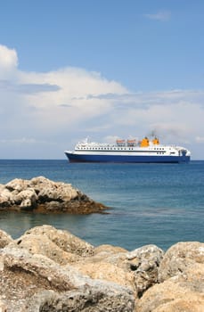 Ferry between Greek islands with rocks in foreground