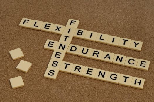 endurance, flexibility, strength - fitness training goals concept, crossword with ivory letter blocks on cork bulleting board