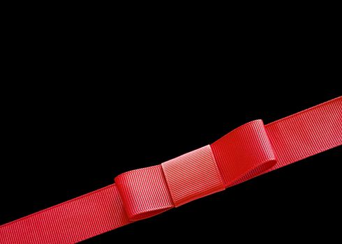 A red ribbon with a bow on a black background. Ready for use on a present.