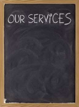our services - white chalk handwriting on blackboard with eraser smudges, copy space below