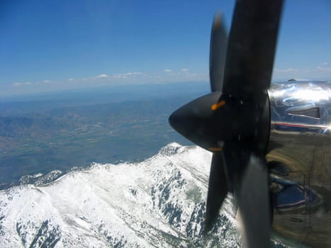 Looking past an airplane propeller to snow covered mountains. 
