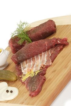 Raw beef roulades with ingredients on bright background