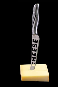 Piece of cheese with cheese-knife - isolated on black background
