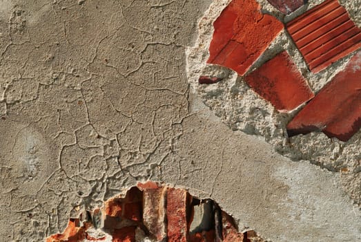 Fragment of a brick wall with the broken plaster